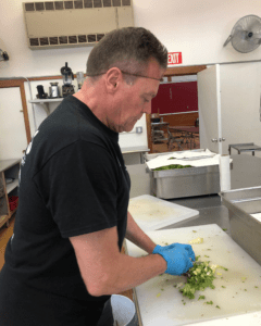 Dana's dad chopping vegetables and looking down