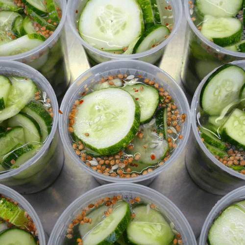 sliced cucumbers in containers with brine and mustard seeds