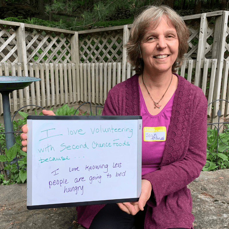 woman holds sign that shows she loves volunteering because it means less people are going to bed hungry