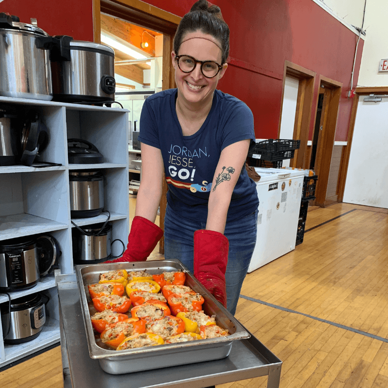 Woman smiled with tray of stuffed peppers