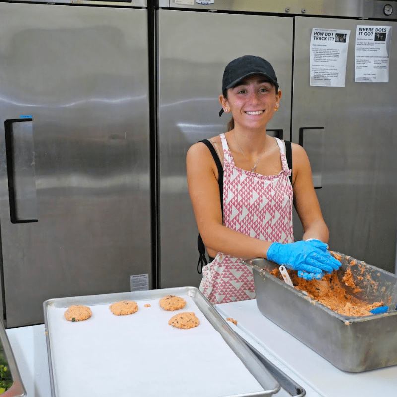 woman smiles while forming salmon cakes