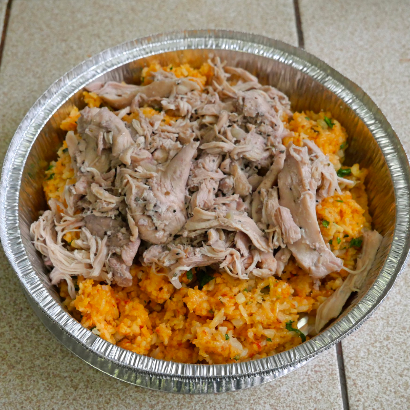 Pulled chicken over rice in a metal to-go container