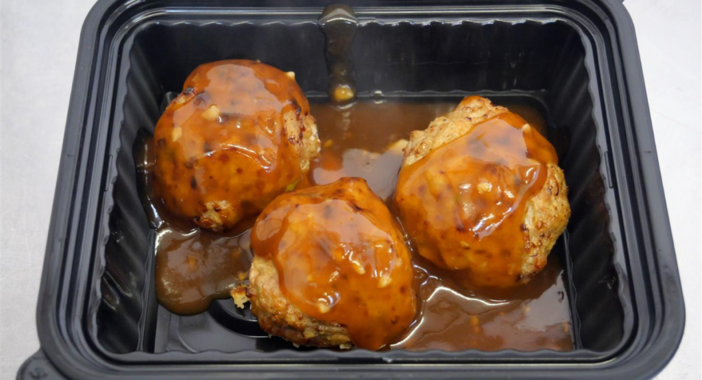 three meatballs with sauce in container