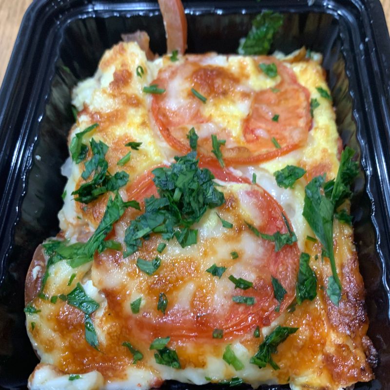 Portion of quiche with tomato on top and parsley garnish