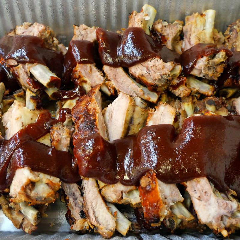 pan of cut ribs with BBQ sauce on top