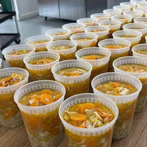 rows of plastic to go containers without lids filled with chicken noodle soup