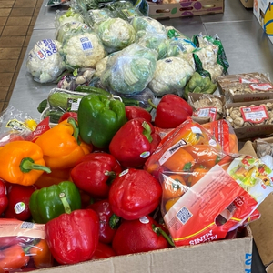 Grocery store bell peppers, packaged cauliflower, and mushrooms in bins fill a table.