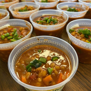 open pint containers of chili with fresh diced green peppers on top