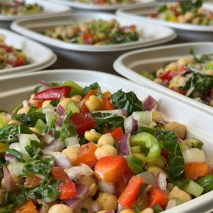 chickpea salad with colorful vegetables and herbs in a compostable to go container.